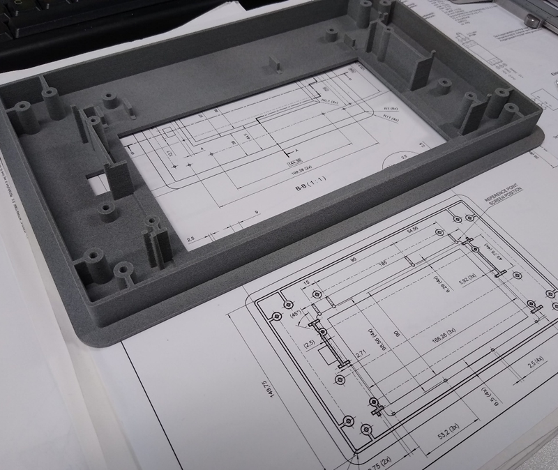 Black machined component on a metal work surface